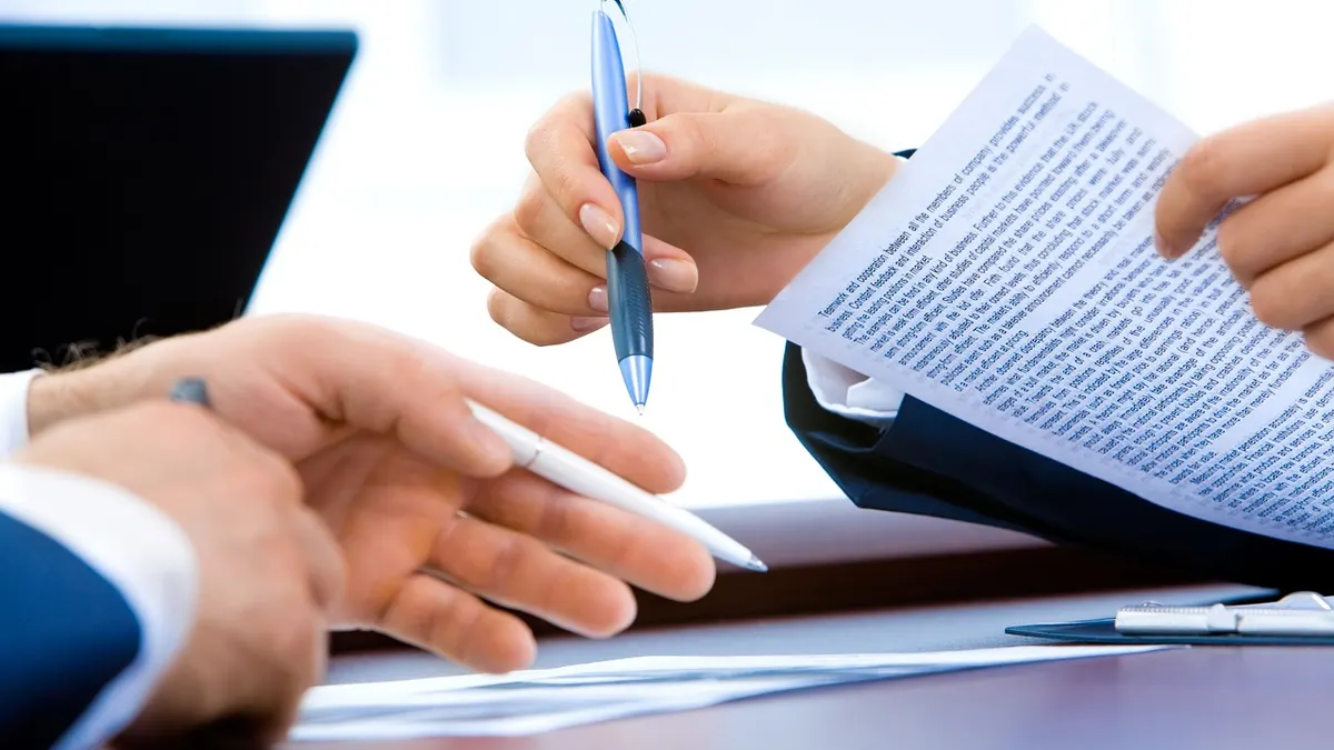 Ordinateur portable au bureau avec une main qui écrit