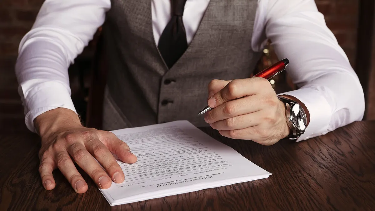 Un homme d'affaires signe un contrat à un bureau.