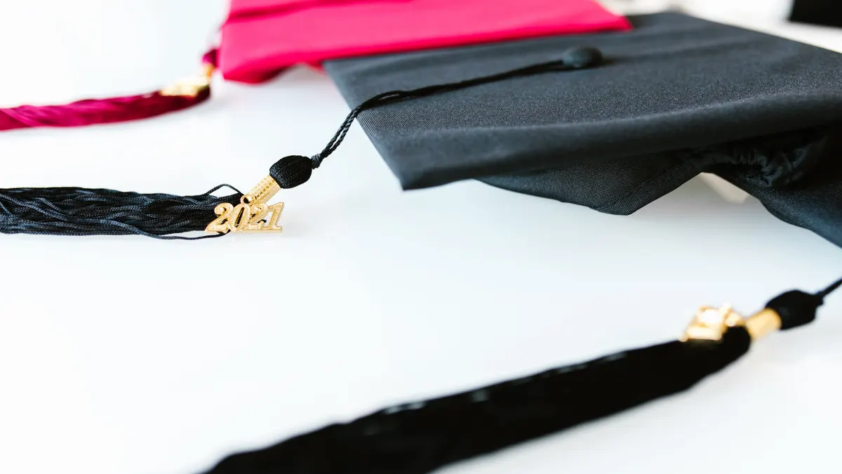 Chapeau de graduation noir sur une table blanche.